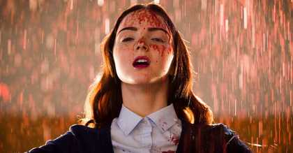 A young female student looking exultant with blood on her face and school uniform while blood rains down all around her.